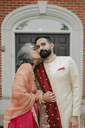 An intimate moment captured between two people in traditional South Asian attire by an arched doorway.