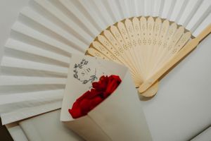 Decorative white paper fan with red flower design against a light background.