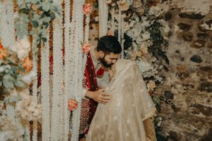 A couple embraces behind romantic floral curtains during their wedding ceremony.