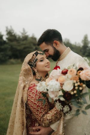 Intimate wedding portrait featuring elegant South Asian bridal fashion and peach floral bouquet.