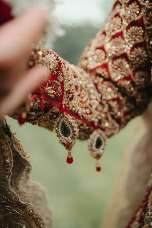 Close-up of intricate red and gold embroidered fabric with jeweled details.