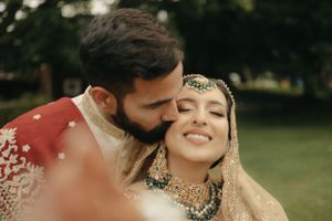 A tender moment captured during a traditional wedding ceremony with ornate South Asian attire and jewelry.