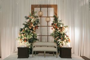 Elegant wedding backdrop with wooden window frame, floral arrangements, and hanging lights.
