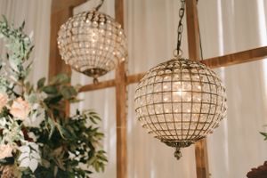 Crystal globe chandeliers hanging with white drapes and floral decorations.