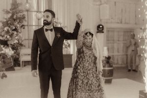 A dancing couple in traditional wedding attire at an elegant indoor reception venue.