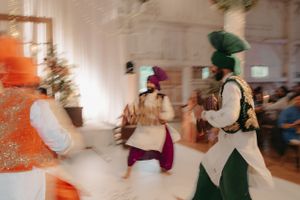 Blurred motion shot of festive wedding reception dancers in colorful traditional outfits.