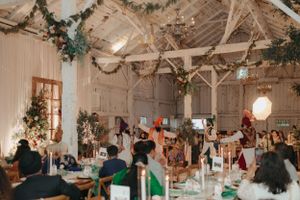 Rustic barn wedding venue decorated with greenery garlands and white drapery.