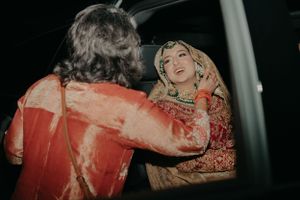 A candid moment captured during a cultural wedding celebration with traditional red attire.