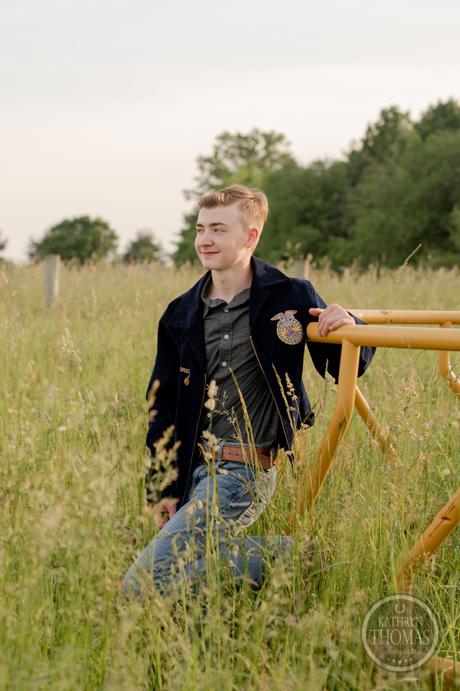 FFA member stands in rustic outdoor setting with yellow railing and natural grassland backdrop.
