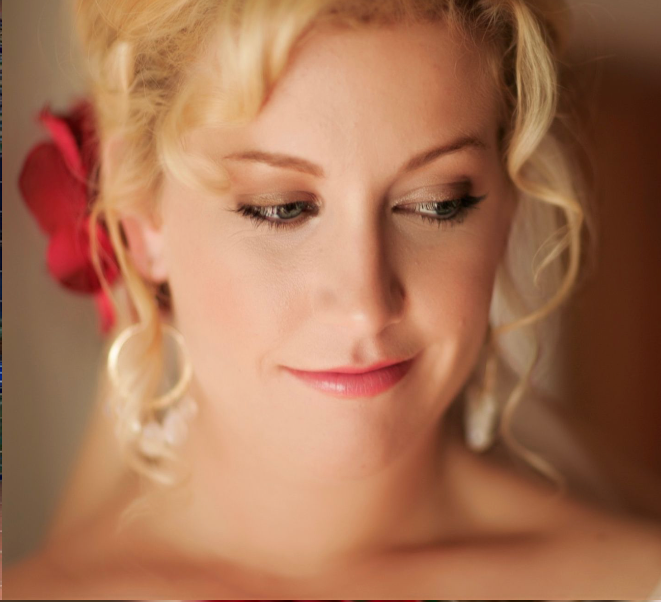 Soft romantic portrait with vintage-inspired hair styling and red flower accent.