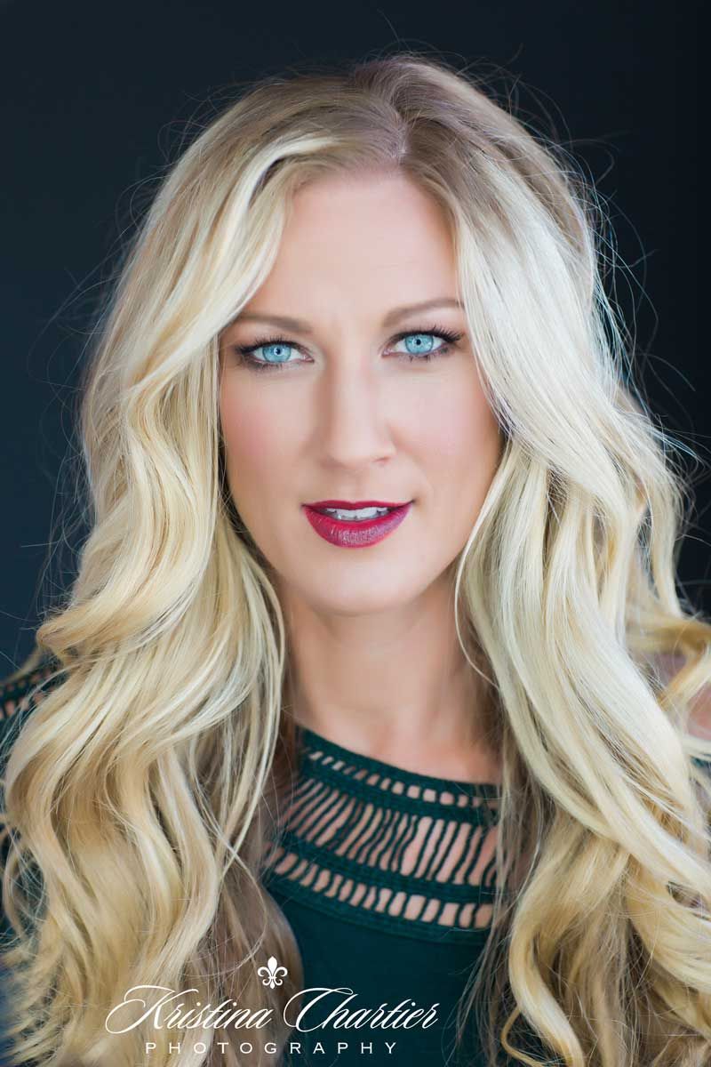 Glamour portrait with blonde hair against dark background.