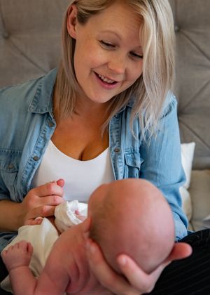 Intimate candid moment between caregiver and infant showing genuine happiness and connection.