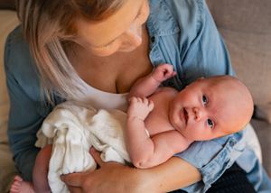 Joyful moment between caregiver and baby wearing white and denim.