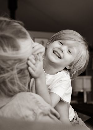 Black and white candid moment of joy and laughter on a sofa.