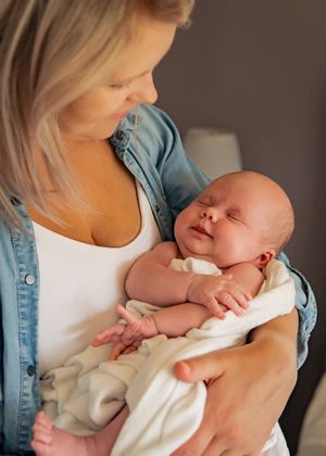 A tender moment of bonding as a newborn baby rests peacefully in gentle arms wearing denim and white.