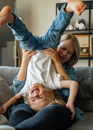 Playful upside-down moment filled with laughter on a grey couch.