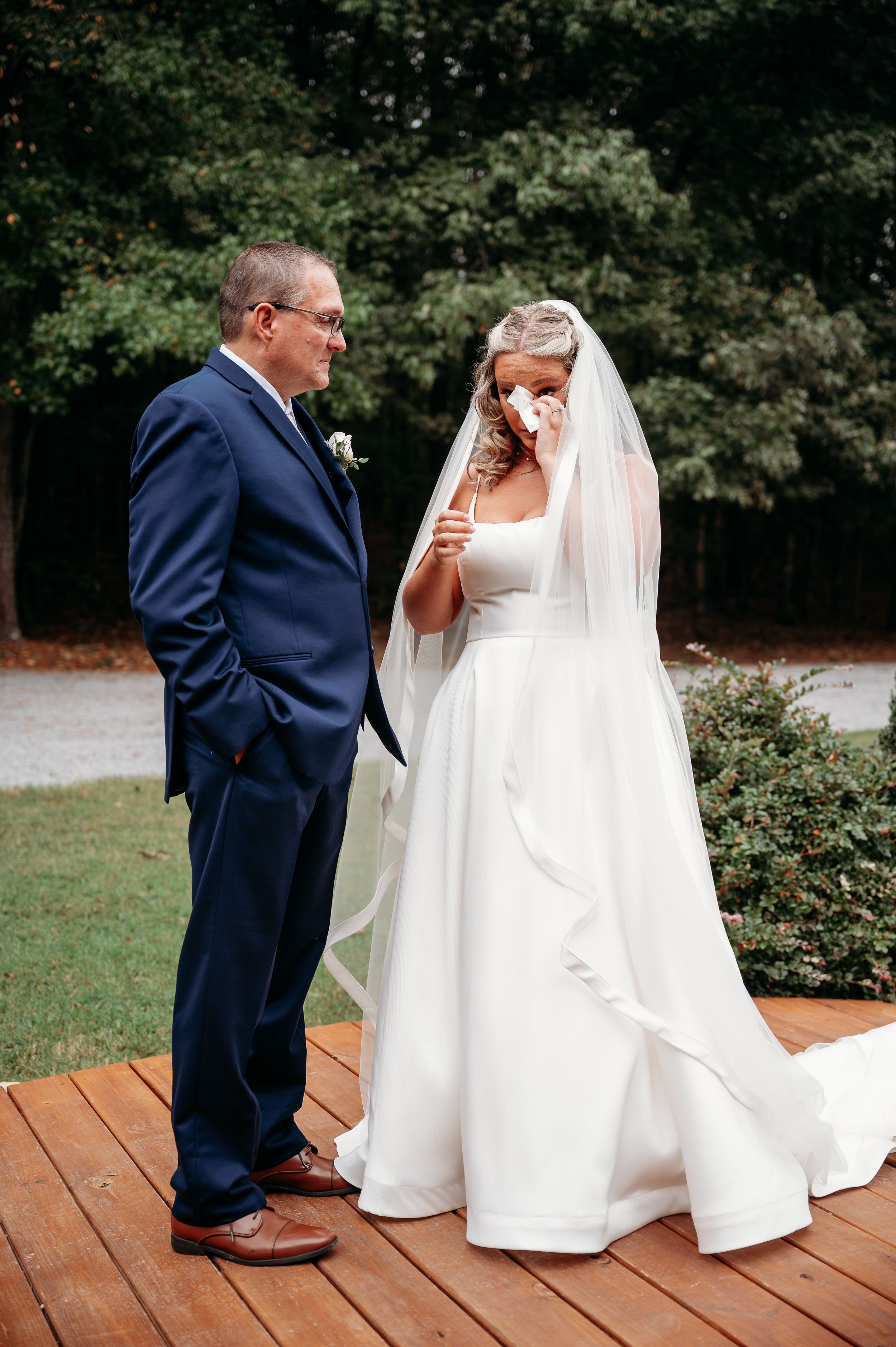 A touching moment captured on a wooden deck during a wedding ceremony.