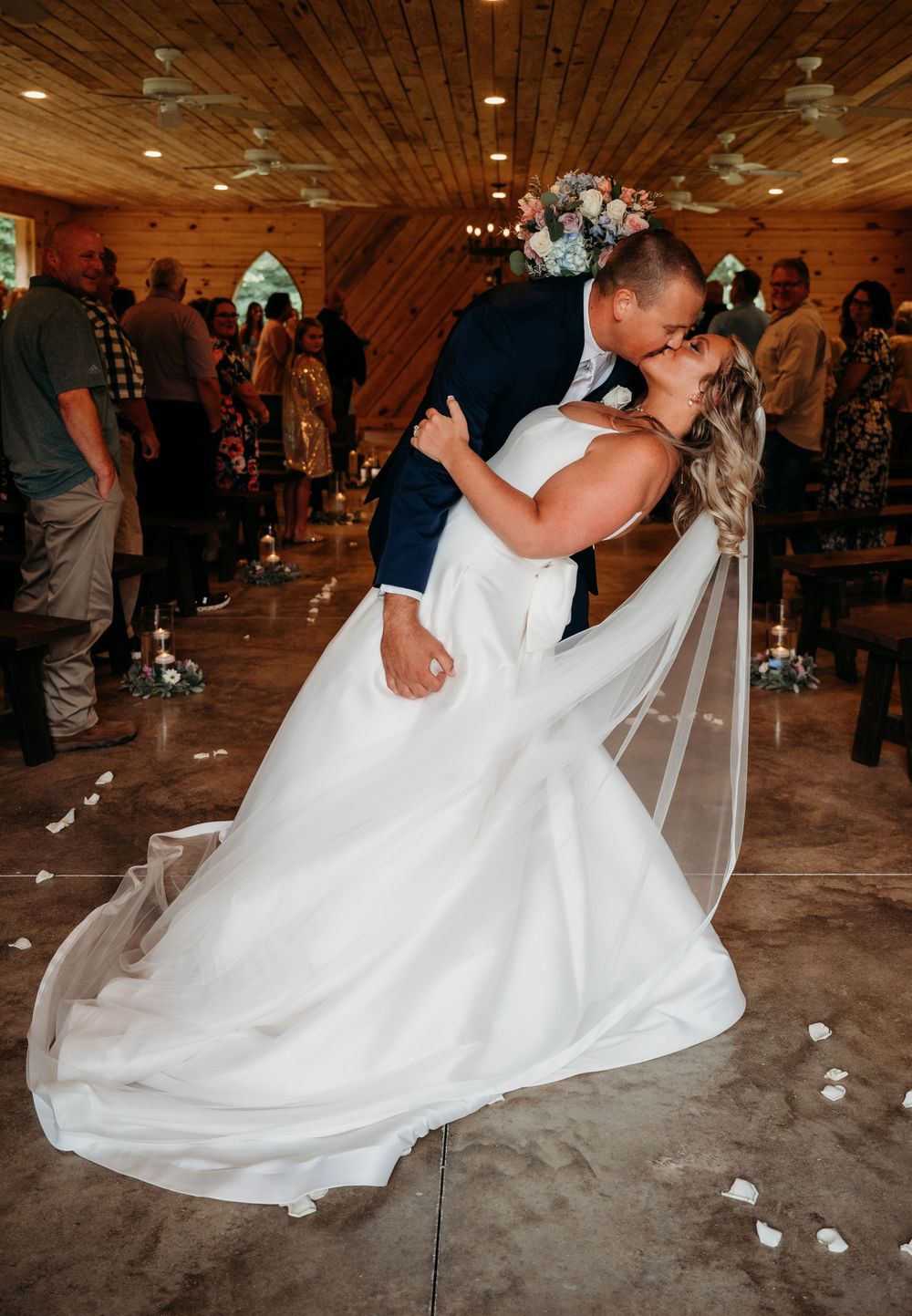 A romantic wedding dance captured in a rustic wooden venue with twinkling lights.
