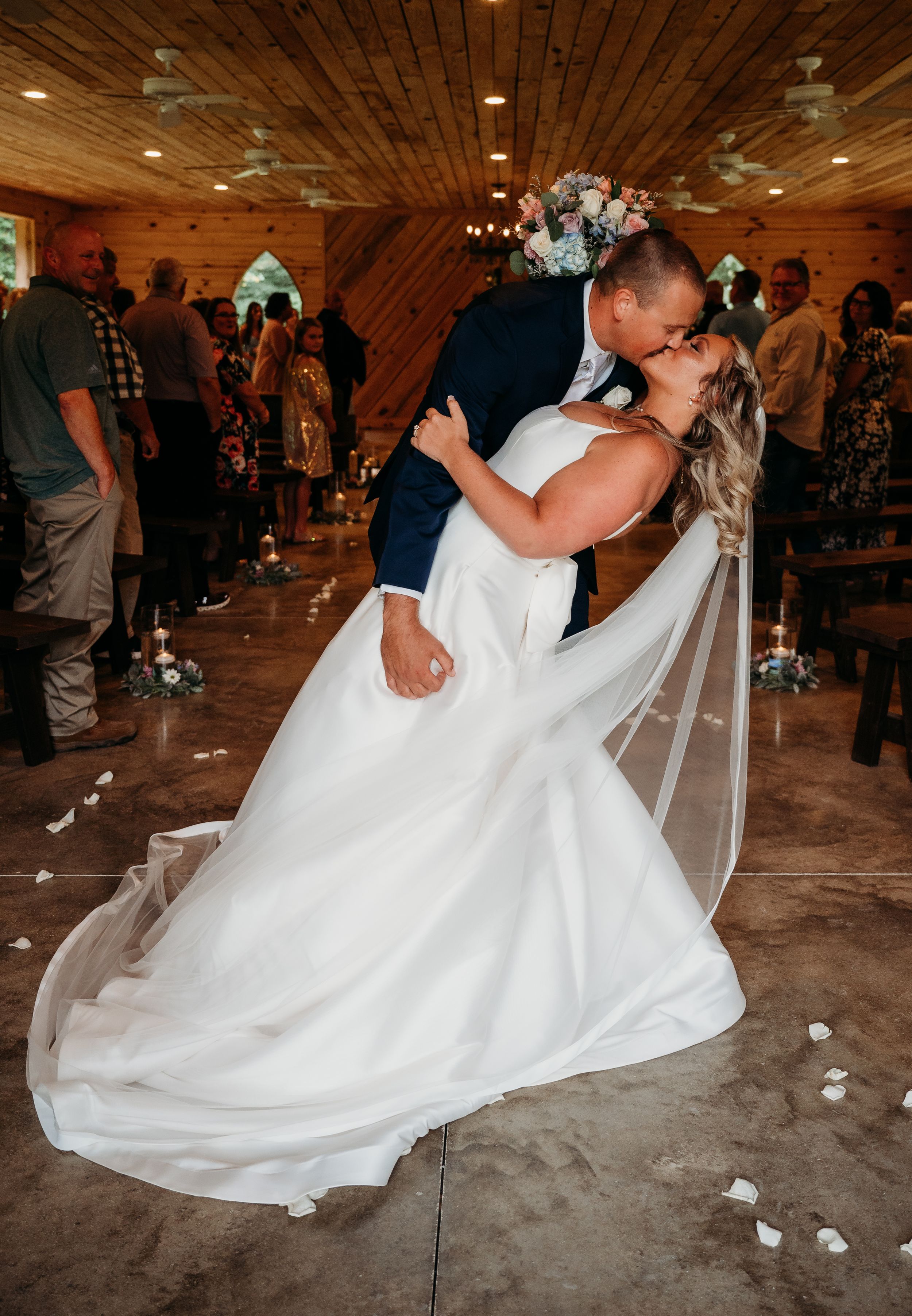 A romantic wedding dance captured in a rustic wooden venue with twinkling lights.