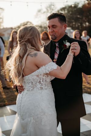 A couple dances together on a black and white checkered floor during golden hour.
