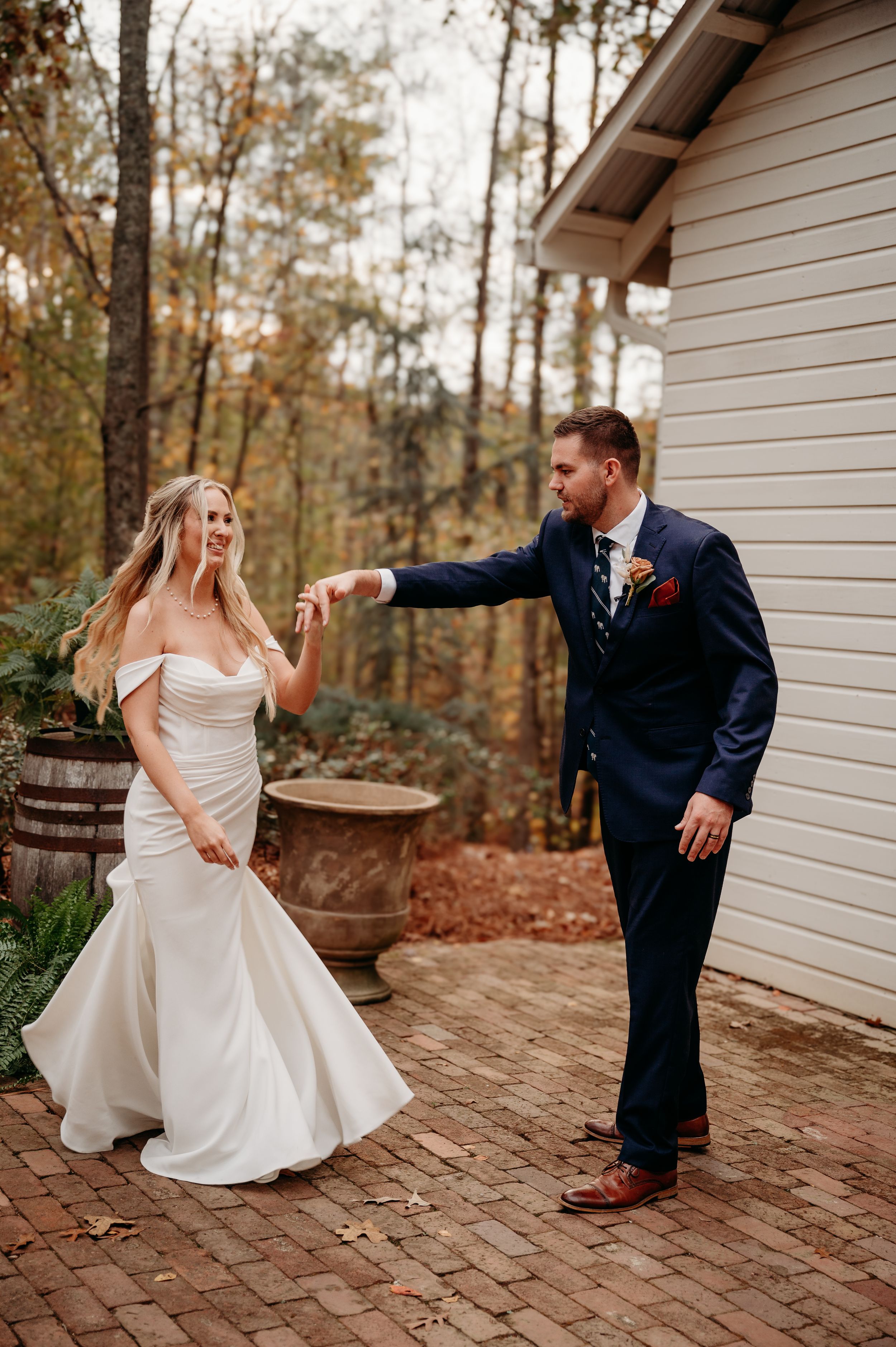 A couple dancing and laughing together on a brick patio during their wedding day.