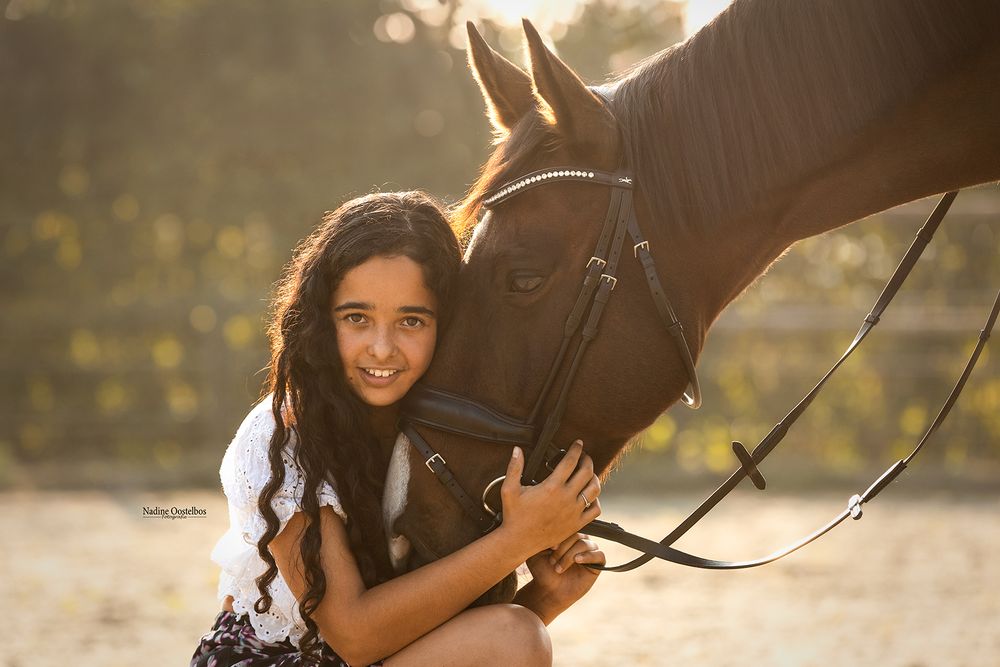 Sunlit outdoor photoshoot showing affectionate interaction between horse and rider.