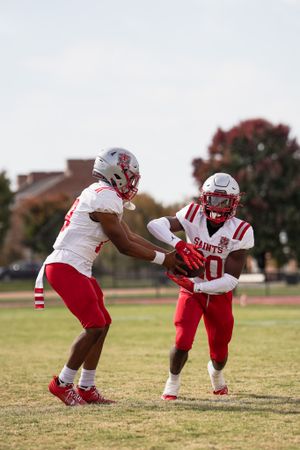 Two football players in red and white uniforms practice drills on the field.