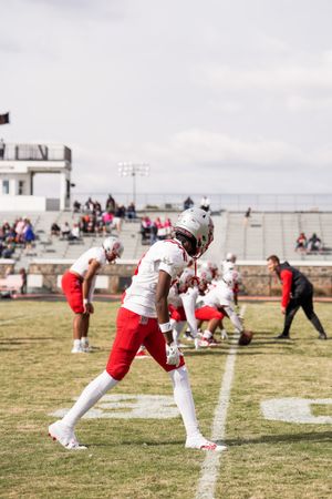 Saints football player in white and red uniform practicing on field.