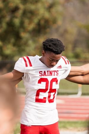 Player wearing number 26 Saints jersey in white uniform stands during game.