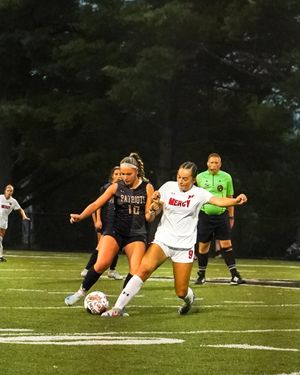 Two soccer players battle for possession of the ball during a competitive match.