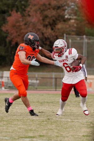 Football players from opposing teams engage in blocking during competitive play.