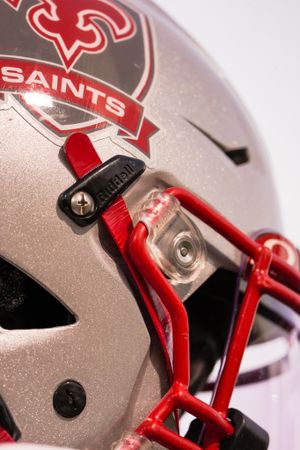 Close-up detail of silver and red Saints football helmet showing team logo and facemask.