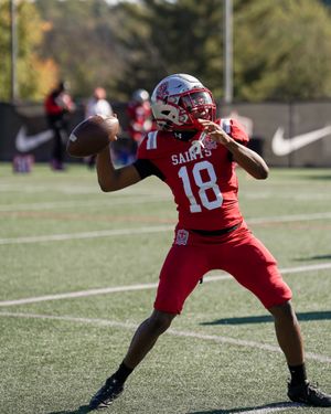 Football player in red Saints jersey number 18 prepares to throw pass during game.