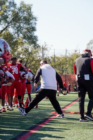 Football coaches and players participate in pre-game warmup drills.