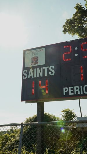 Concordia Park Saints scoreboard display with digital numbers against blue sky.