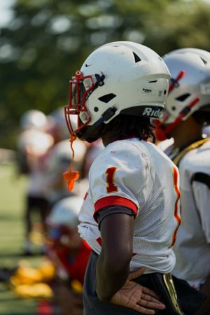 Football players line up wearing white helmets with red accents during game.