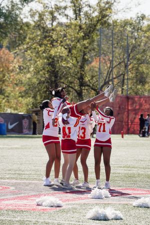 Cheerleaders form a pyramid formation during an outdoor performance on a sports field.