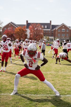 Football player in red and white uniform demonstrates athletic stance on field.