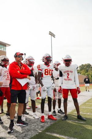 Football team and coaches gathered on sideline during game.