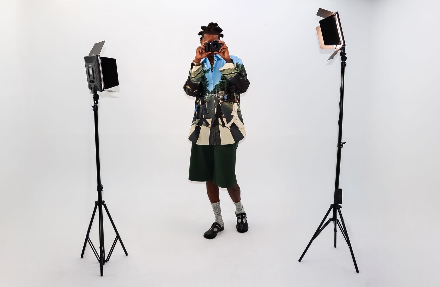 Behind-the-scenes studio photo with two lighting stands and someone in traditional Bavarian folk dress holding a camera.