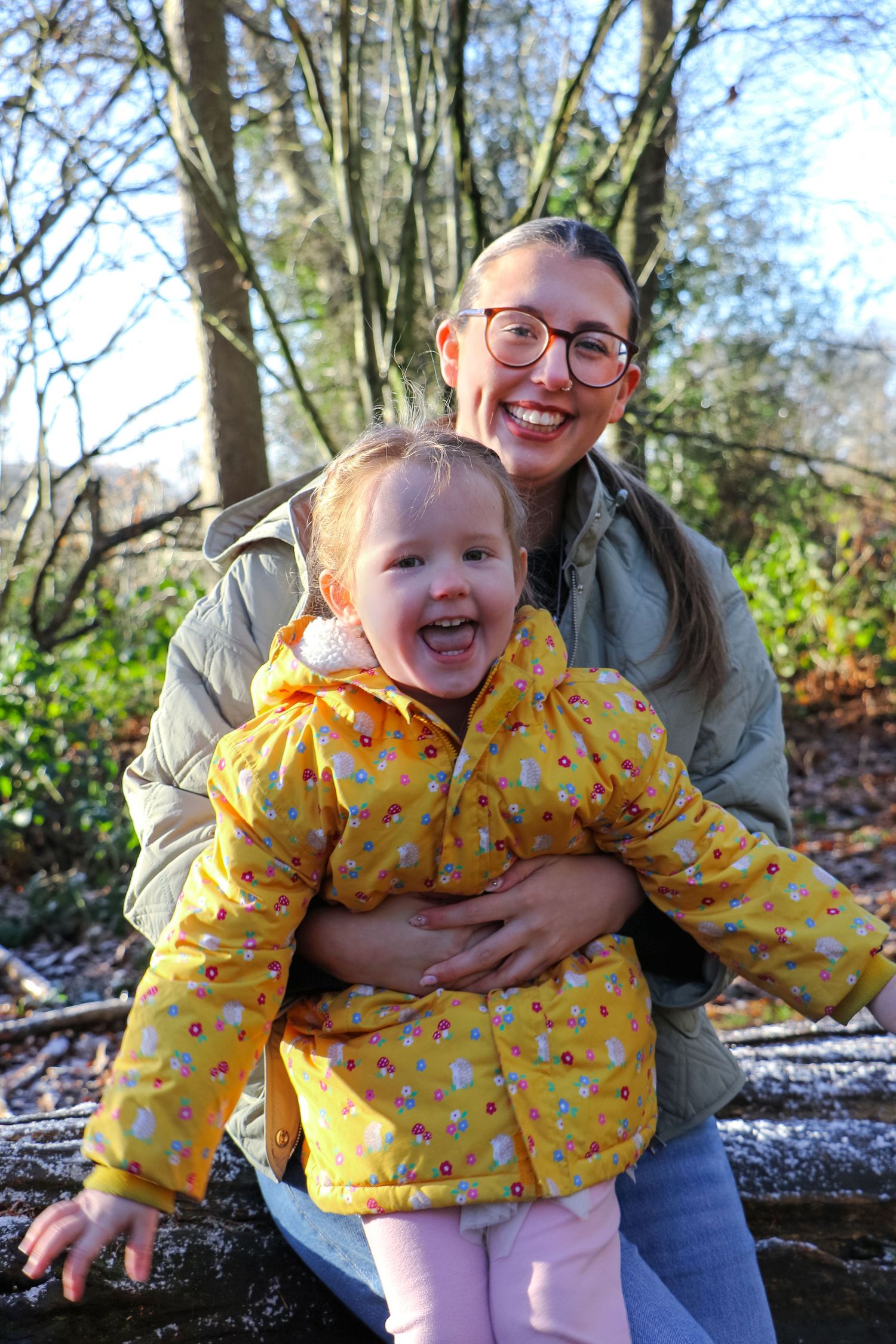 A joyful outdoor moment captured in the woods with a bright yellow raincoat on a sunny autumn day.