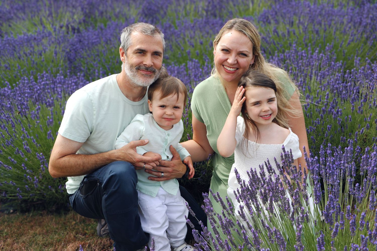 A family poses together in a blooming purple lavender field on a sunny summer day.