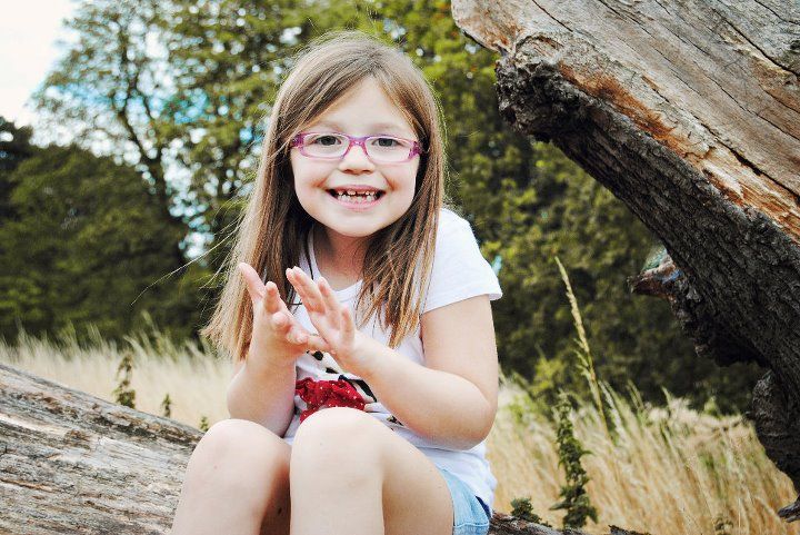 A series of outdoor portrait photographs taken in a natural setting with tall grass and fallen logs.