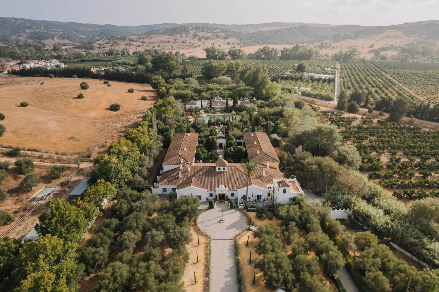 Aerial view of Spanish-style villa estate surrounded by olive groves and countryside.