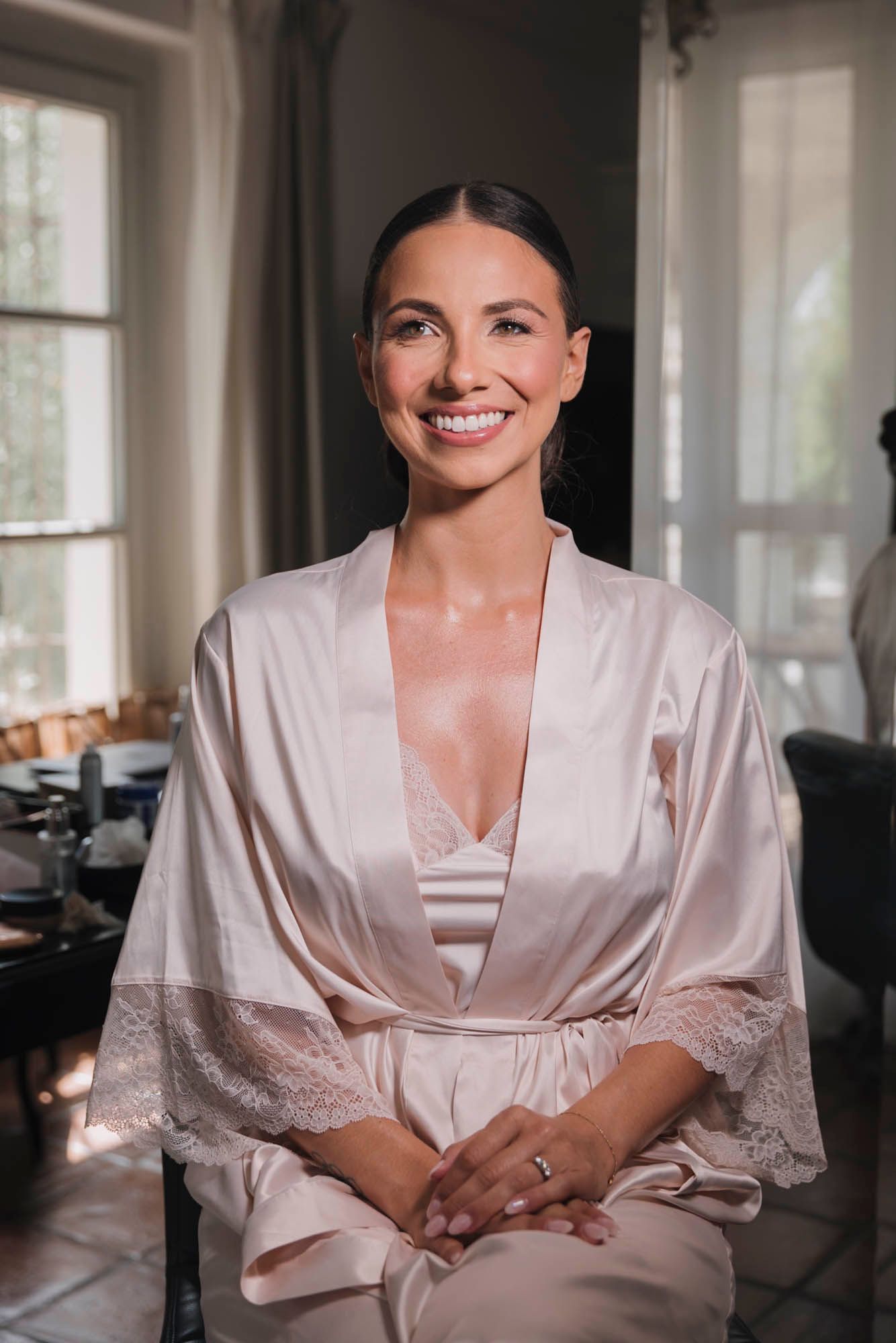 Bride wearing silk robe getting ready on morning of wedding.