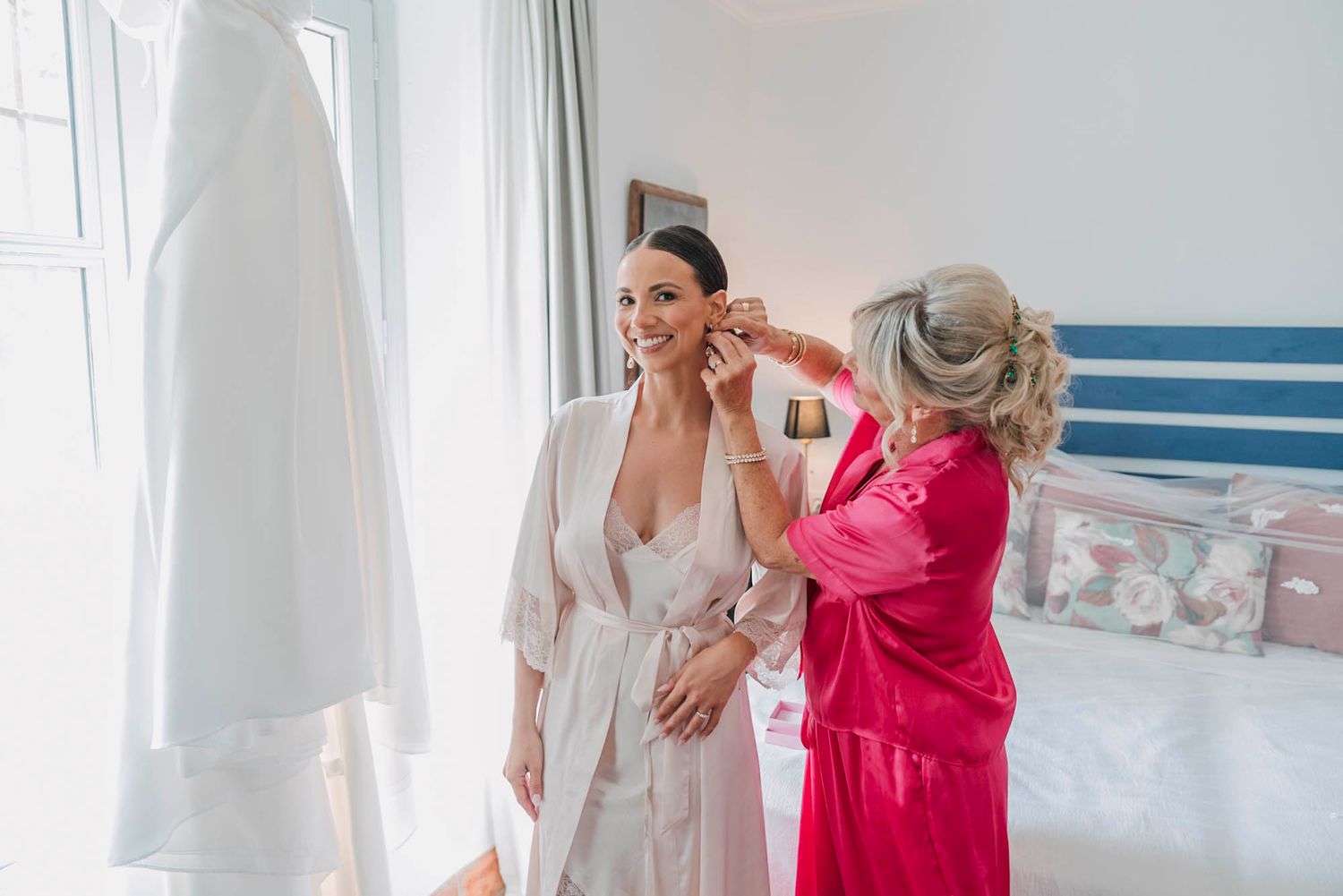 Getting ready scene with wedding dress and two people in robes.