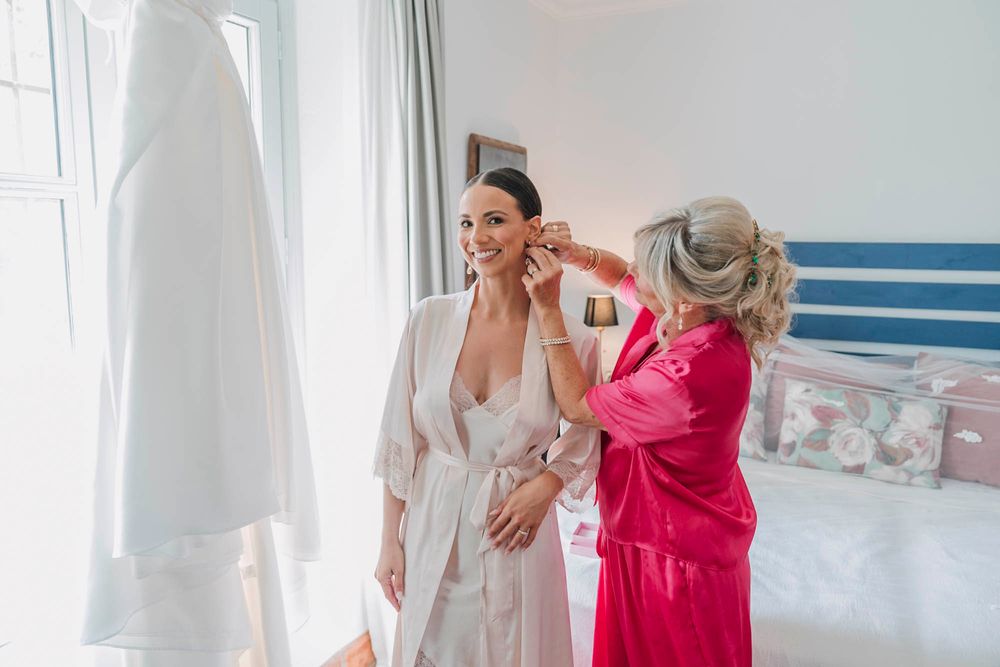 Getting ready scene with wedding dress and two people in robes.