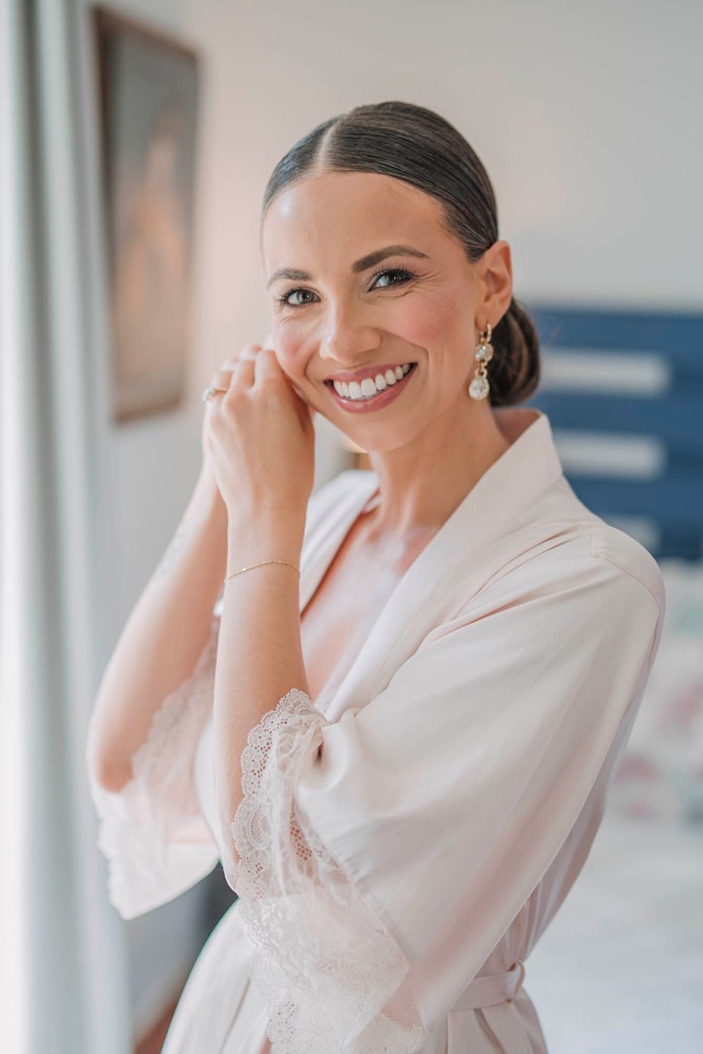 Wedding preparation moment in white silk robe with elegant hair and makeup.