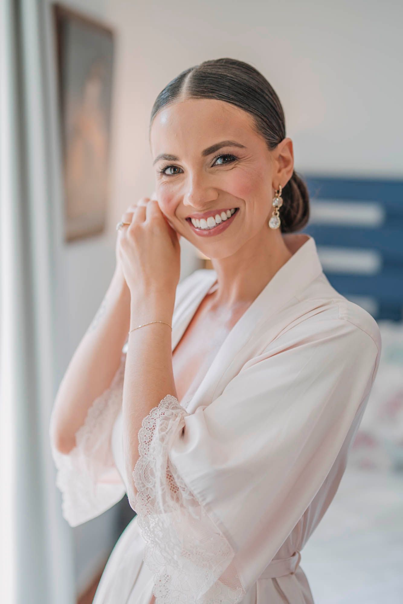 Wedding preparation moment in white silk robe with elegant hair and makeup.