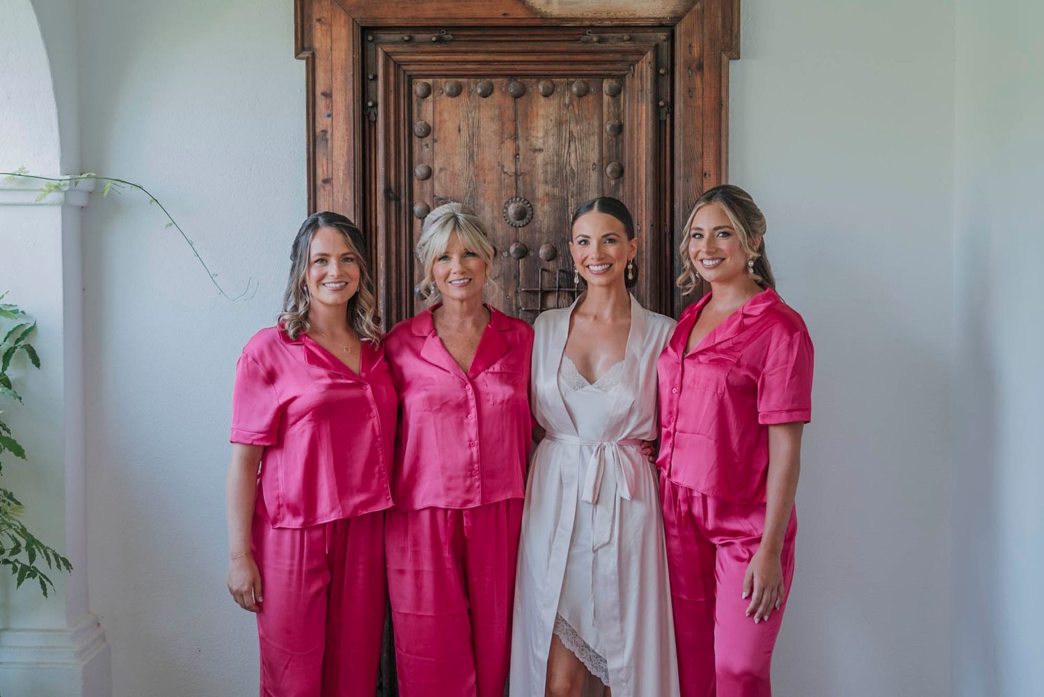 Group photo of bridal party wearing matching pink silk pajama sets.